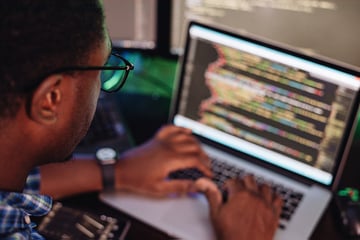 Black male in front of computer screen coding mobile app web development computer programming